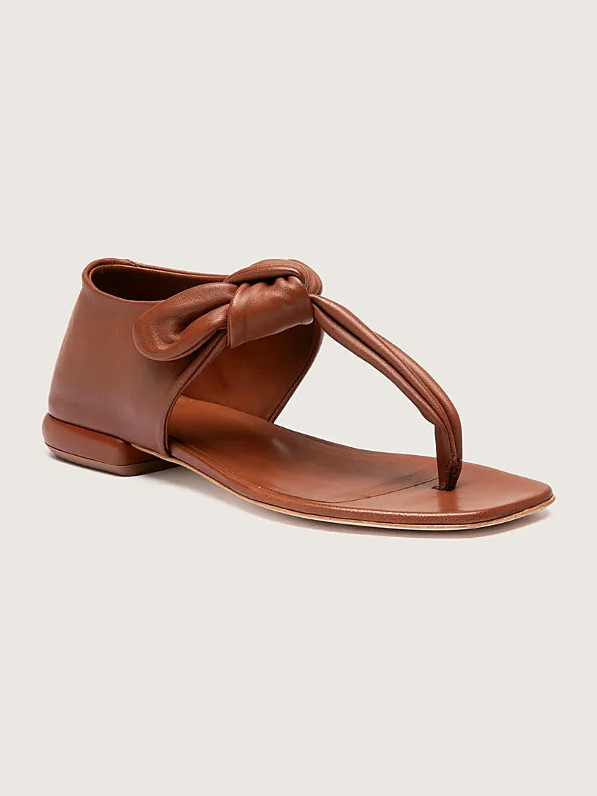 Brown thong sandals pair arranged together on a neutral ground